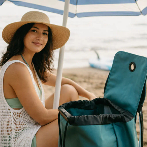 Mujer en la playa sacando una esterilla de un carro de compra Rolser con bolsa color sea coast