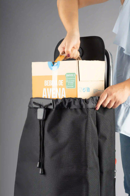 Vista frontal del carro Rolser azul-negro siendo cargado con caja de bebida alimenticia