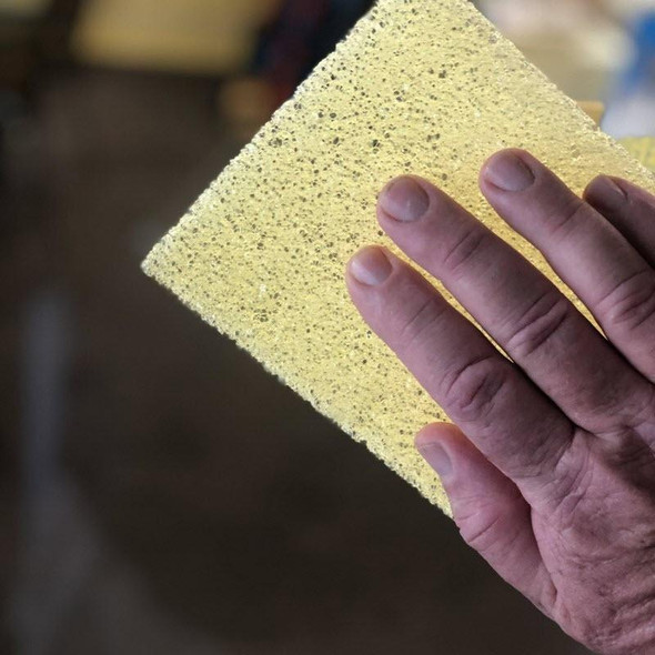 J.Racenstein Poly Pad - 5in x 7in - Scrubbing Pad Honeycomb Han Dee, yellow textured scrubbing pad held by a person's hand.