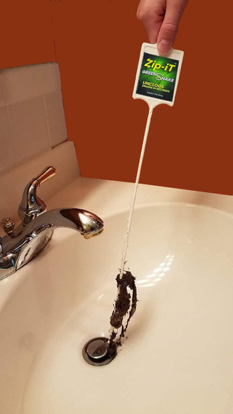 J.Racenstein Zip-It Green Snake Drain Cleaner, hand holding the green snake drain cleaner with a long flexible white rod extracting hair and debris from a bathroom sink drain.