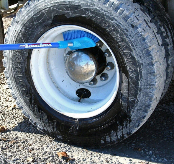 J.Racenstein Brush BiLevel 10in Blue Soft FlowThru, cleaning a vehicle's tire with a long-handled brush.