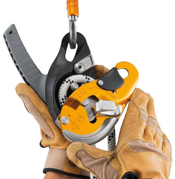 Petzl Descender ID, climbing and rescue descender device with orange and black safety features, held by a person wearing protective gloves.