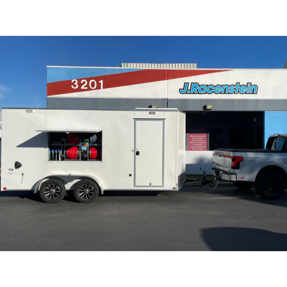 ProTool Enclosed Pressure and Soft Washing Drone Trailer, white enclosed trailer with pressure washers, soft wash equipment, and hoses, parked outside J. Racenstein store.