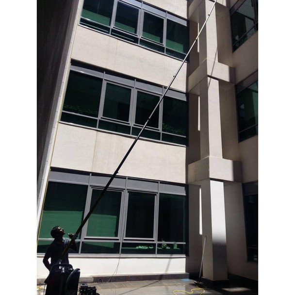 Gardiner Pole Systems Gardiner Ultimate 57ft Tele Pole HM Carbon Kevlar, being used for window cleaning or maintenance on a building exterior.