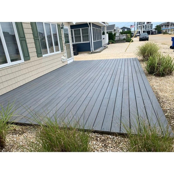 J.Racenstein Deck & Wood Stain Barnegat Gray Gallon DRP, a finished outdoor deck with Barnegat Gray stain installed on wooden planks next to a house.