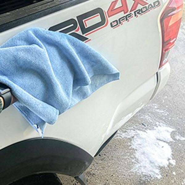 J.Racenstein ProTool Blue MicroFiber Towel 20 Pack, microfiber towel draped on the side of a white vehicle near a sticker with red and black text