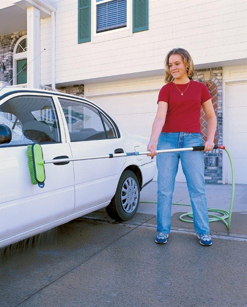J.Racenstein Brush 10in Green Very Soft for FlowThru, a cleaning brush with a green handle and soft bristles, used by a woman washing her car outside a house.