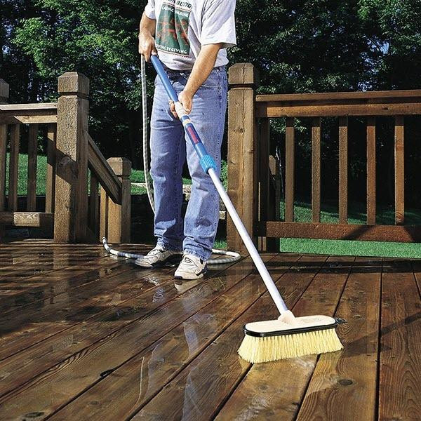 J.Racenstein HydraSoar Stiff 10in Beige FlowThru Brush, cleaning a wet wooden deck outdoors.
