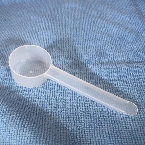 ProTool Scoop for Measuring 1/2oz - 14.8cc, clear plastic measuring scoop with a long handle on a textured blue surface.