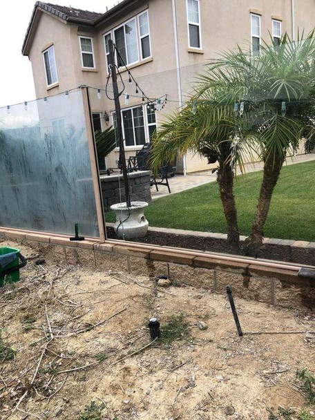 Sorbo Hard Water Stain Remover 5oz, image of a backyard with a glass fence, palm trees, and a house in the background.