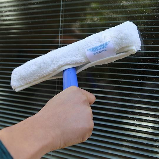 Ettore All Purpose Washer 10 inch, close-up of a hand holding a white microfiber cleaning tool with a blue handle, cleaning window blinds.