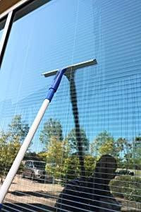 Ettore ProGrip Window Cleaning Kit, window cleaner with a squeegee being used to clean a glass window outdoors.