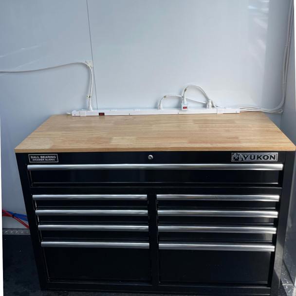 ProTool Enclosed Pressure and Soft Washing Drone Trailer, a black Yukon tool cabinet with multiple drawers and a wooden top, connected to electrical outlets for power tools.