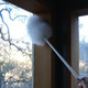 Ettore Lambswool Duster with 28-inch handle, white fluffy duster being used to clean a window frame.
