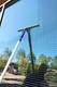 Ettore ProGrip Window Cleaning Kit, window cleaner with a squeegee being used to clean a glass window outdoors.