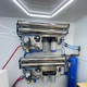 ProTool Enclosed Pressure and Soft Washing Drone Trailer, industrial water filtration and spraying system with metal pipes, pressure gauges, and blue tubing.