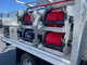 ProTool Drone Pressure Washing Flatbed Skid, image of a stainless steel pressure washing equipment with red and blue hoses mounted on a flatbed trailer for industrial cleaning uses.