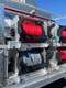 ProTool Drone Flatbed Skid - V-SPEC, close-up of an aluminum flatbed skid fitted with organized red and black hose reels, mounted controls, and stainless steel framing.