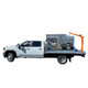 ProTool Drone Flatbed Skid - V-SPEC, truck-mounted flatbed skid with equipment compartments, dual drone spray systems, and an orange hydraulic boom.