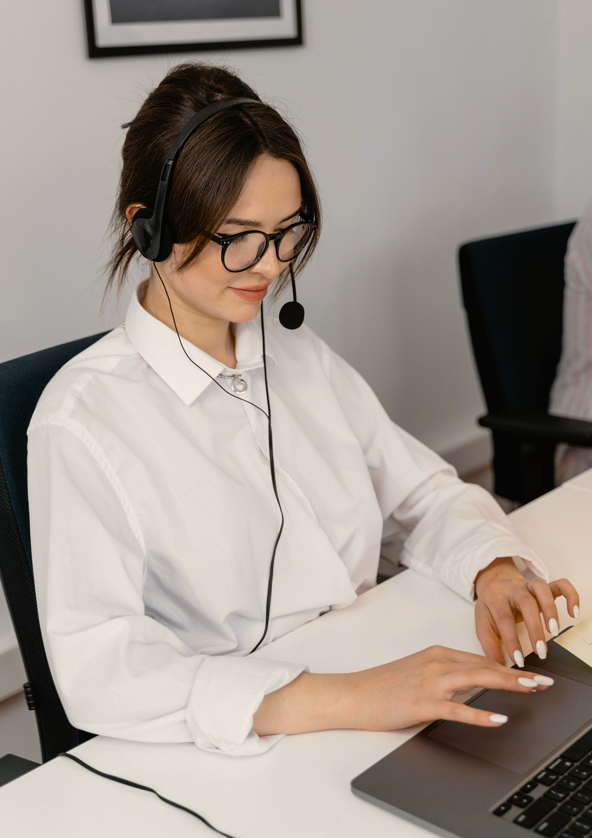 A woman wearing headphones sits at her desk, working intently on her laptop, embodying concentration and productivity.