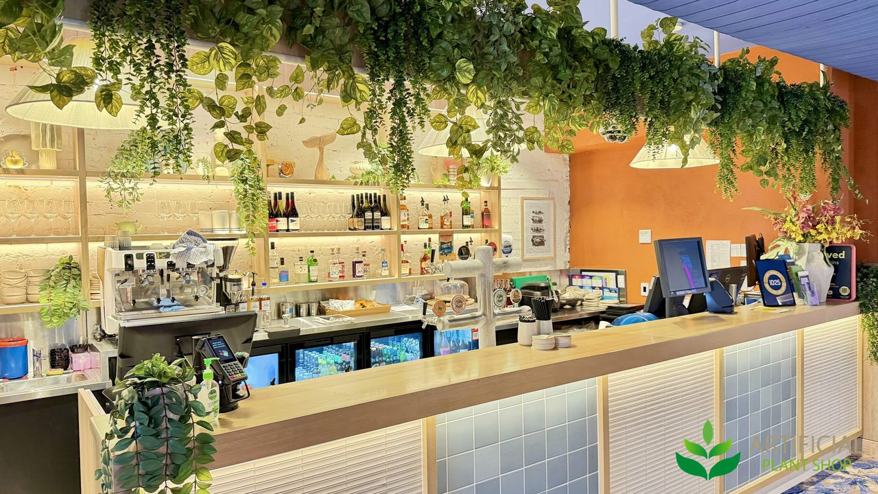 fake trailing greenery hanging above a cafe bar counter