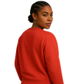 She wearing a poppy red recycled sweatshirt in a relaxed fit, viewed from the side.