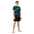 Front view of an athletic male model wearing the fitted Anuri Ignite Men’s Recycled Short Sleeve Rash Guard showcasing the premium all-over bold graphic print.