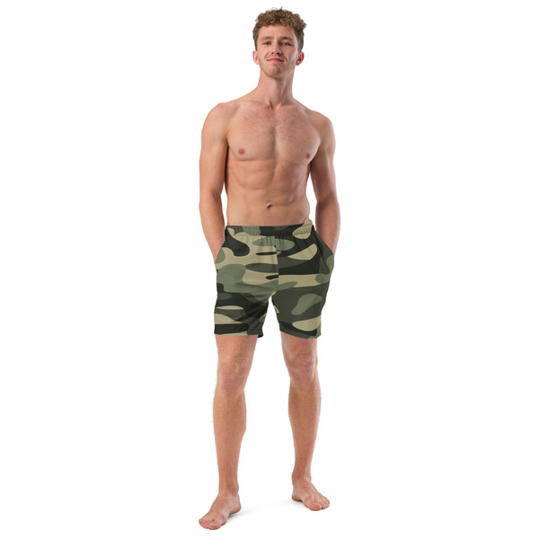 Front view of an athletic male model wearing the Anuri Flow Men's Recycled Swim Trunks in a premium green and black camouflage pattern.