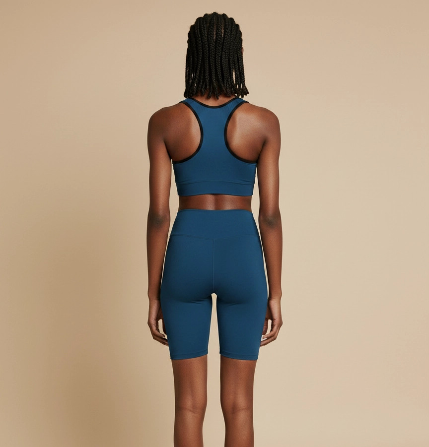 Back view of a model wearing the Anuri Powerform Padded Sports Bra in Crown Blue with black contrast trim and matching high-waisted shorts.