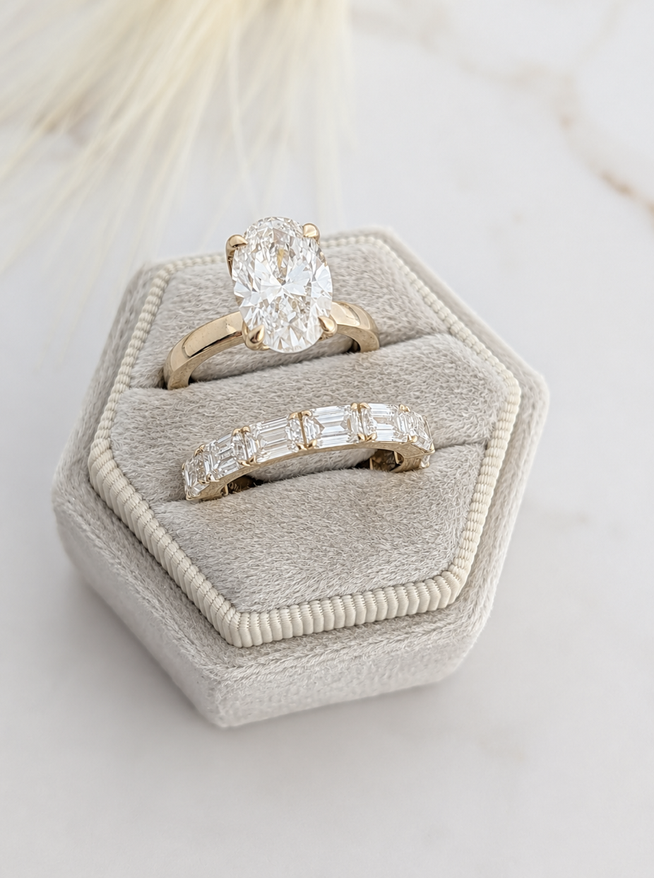 Oval engagement ring and diamond wedding band displayed in a ring box