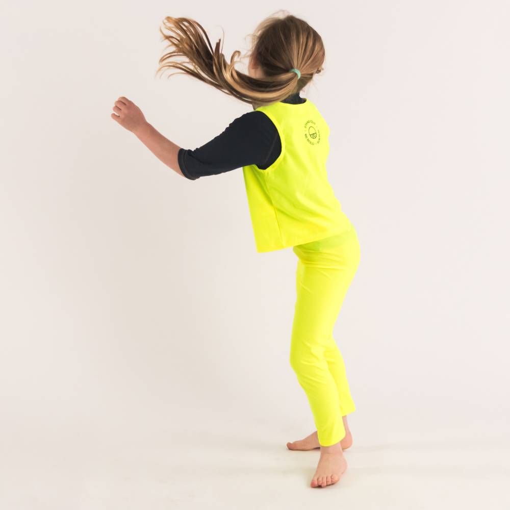 Girl in Neon Yellow Swim leggings with Neon Yellow Be Seen Over Vest - jumping shot