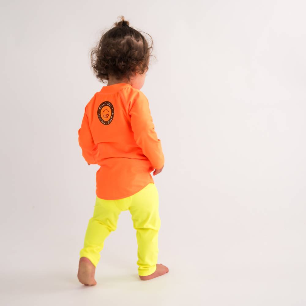 Toddler standing in Neon Yellow Swim leggings with Neon Orange Swim Rash Vest - back shot