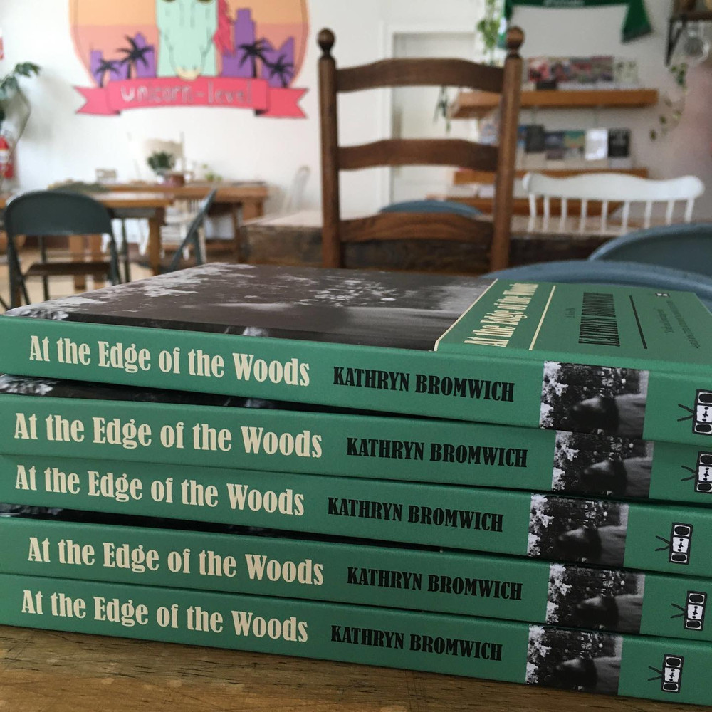 At the Edge of the Woods (Hardcover) a novel by Kathryn Bromwich, Two Dollar Radio, 2023, stack of books showing spine