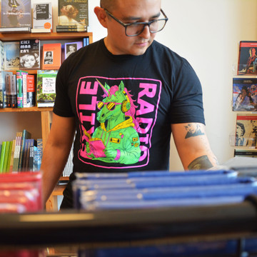 Gus Moreno, author of This Thing Between Us, modeling an Exile Radio T-Shirt at Exile in Bookville, April 2024.