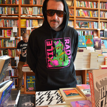 Zachary Pace, author of I Sing to Use the Waiting, models an Exile Radio hoodie in Exile in Bookville, April 2024.