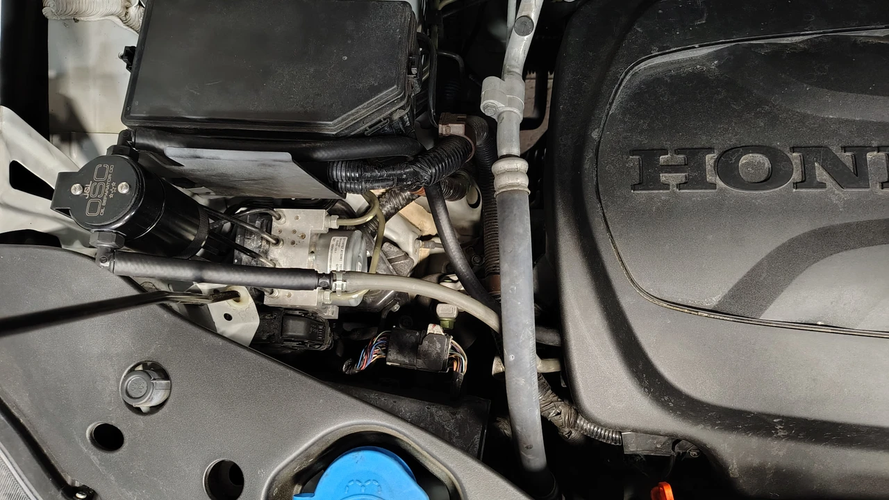 Close-up view of the J&L oil separator unit secured inside a Honda engine compartment.
