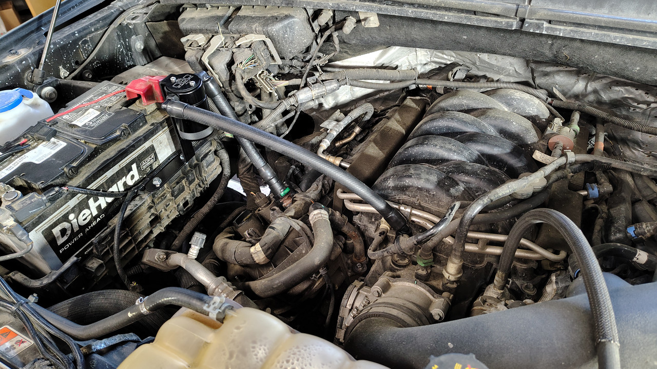 Wide-angle view of the vehicle engine bay highlighting the final placement of the J&L oil separator kit.