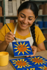 Artisan painting a blue sun relief tile.