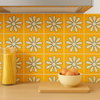 Orange daisy tile backsplash in a kitchen with a pasta jar, cutting board, and bowl of eggs.