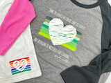 Off-White baseball style tee with pink sleeves with a rainbow striped graphic in the bottom right corner overlapped by a white heart graphic with missing spaces to reveal the rainbow stripes through it, is overlapping a gray baseball style tee with dark gray sleeves with a large graphic in the middle of multiple shades of green stripes overlapped by a white heart graphic with pieces missing to reveal the green stripes through. Above the graphic reads "One is loved because one is loved." Below the graphic reads, "No reason is needed for loving." -Poulo Coelho. All graphics and text created with EasyWeed Heat Transfer Material.