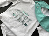 Image of a white baby onesie with the logo “In My Debut Era” in Varsity Letters using EasyWeed Electric Teal and Spearmint creating a two-tone effect.