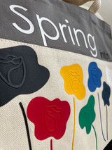 Image of a closeup of a beige and black canvas bag showing stylized flower buds made of EasyWeed Stretch on top of detailed flower heads Brick 600 heat transfer material, which gives it an embossed look.