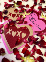 Image showing loose red rose petals and three multilayered heart-shaped cards laying among the rose petals decorated using red Twinkle solid heart with “X, a Heart Shape, X, a Heart Shape” cut out, a heart outline with “My Valentine” and a plain cardstock heart with “X, a Heart Shape, X, a Heart Shape”.