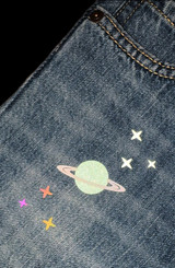 Image of jeans with a planet graphic using Aqua Black EasyReflective Heat Transfer Vinyl and Dark Gray EasyReflective Heat Transfer Vinyl illuminated and reflecting.