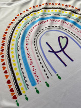 Image shows rainbow created with different line patterns and colors on a white shirt enveloping the Happy Crafters logo.