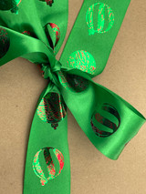 Image of a partial view of a green satin ribbon with round holiday ornaments applied to it using Red and Green Happy Crafters Two Step Foil