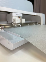 Closeup of the Cricut® Venture cutter cutting a piece of Silver SmartHTV Glitter