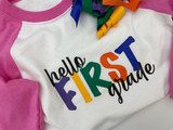 Image of a pink and white children’s baseball shirt with a logo reading “Hello First Grade” using prime colors of SmartHTV.