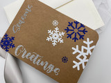 Image of brown cardstock with snowflake logos and “Seasons Greetings” using Navy, White and Silver SmartHTV Glitter.