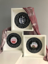 Image of three, stacked white shadow-box frames with the logo of “vinyl record” in each using BlackBoard. Each vinyl record depicts - handwritten in chalk - the dates and intimate moments to remember.